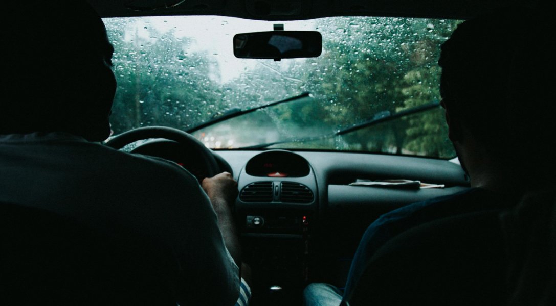 Inside a car during rain, two people are visible.